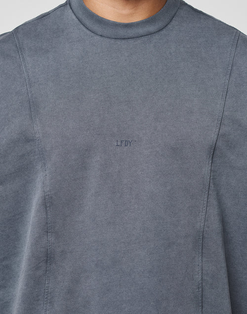 A person wears the Heavy Muscle Tank by LIVE FAST DIE YOUNG, featuring an oversized fit in faded grey with a small LFDY frontprint. Only the upper torso and neck are shown, without any visible background.