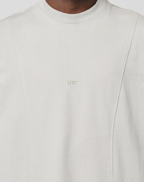 A close-up of a person wearing the LIVE FAST DIE YOUNG Heavy Muscle Tank in light grey, made from soft Baumwolle with subtle panel stitching and a small LFDY frontprint centered on the chest.