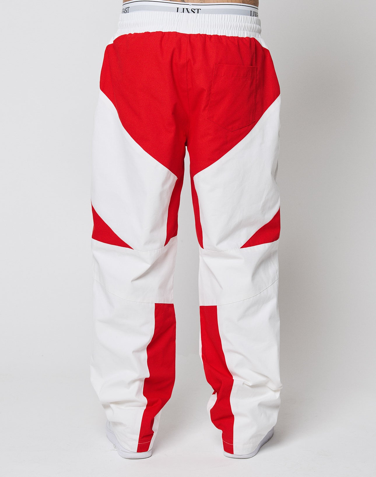 The LFDY Cross Pants by LIVE FAST DIE YOUNG are loose-fitting with bold red and white geometric color blocking. They feature an oversized fit, a white waistband with black text, Stick Applikationen, and a single back pocket.