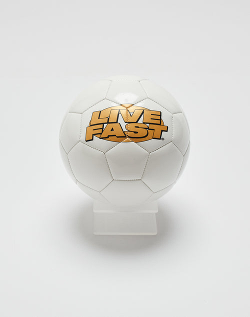 The Live Fast Soccer Ball by LIVE FAST DIE YOUNG features black stitching, bold yellow and black LIVE FAST lettering, and a distinctive logo print, all displayed on a clear stand against a plain white background.