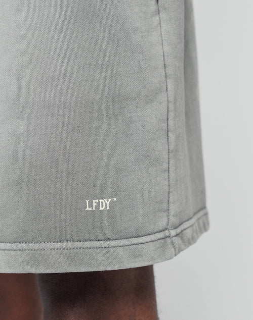 Close-up of the Basic Sweat Shorts by LIVE FAST DIE YOUNG in regular fit, featuring the white LFDY logo embroidered near the hem, worn by a person with dark skin.