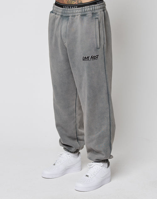 Person wears LFDY Europe Run Jogger by LIVE FAST DIE YOUNG, featuring LIVE FAST text on the left thigh, elastic cuffs, and a matching waistband. Styled with white Nike sneakers against a plain white background highlighting the loose fit.