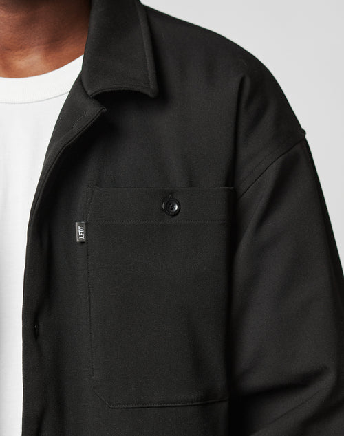 Close-up of a person wearing the black Padded Casual Shirt by LIVE FAST DIE YOUNG over a white t-shirt. Only the left chest and shoulder are visible.