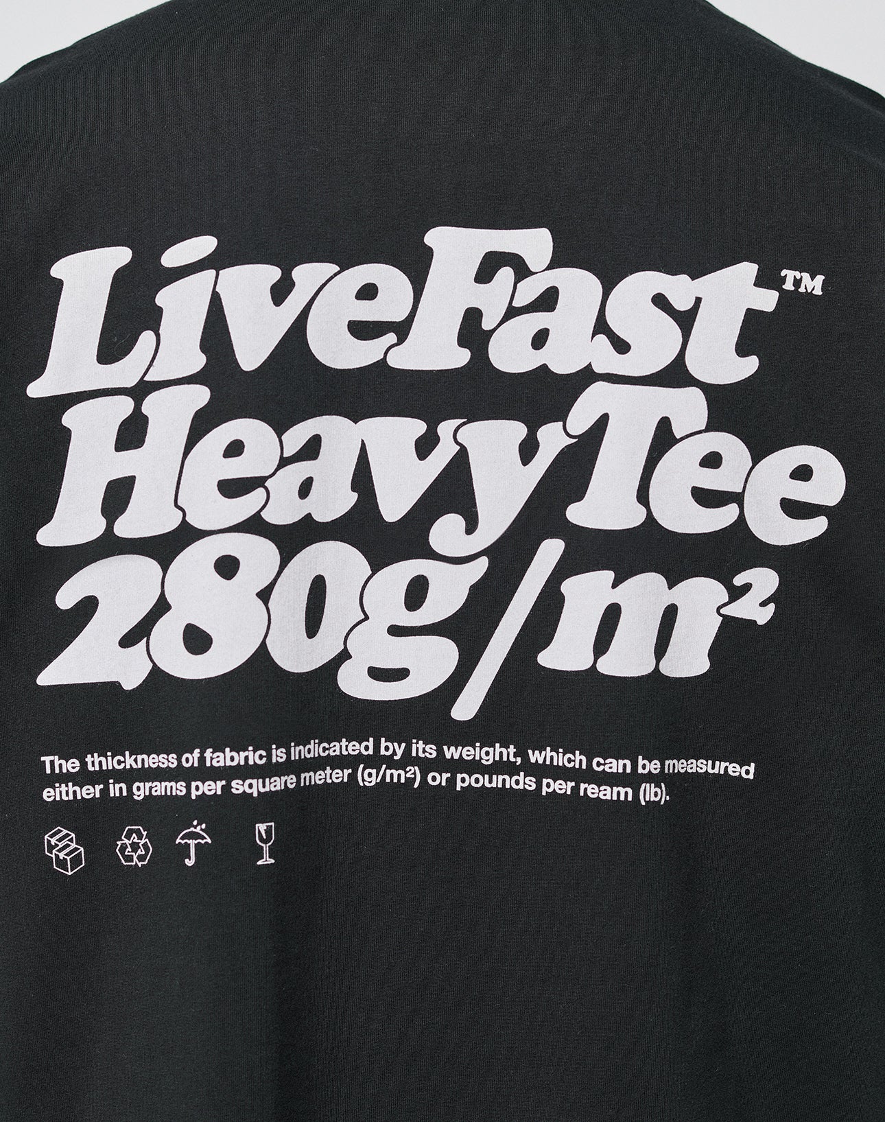 The LIVE FAST DIE YOUNG Basic 280 Tee is a black oversize fit cotton t-shirt with a bold white front print, fabric thickness info in small text, and washing, recycling, and handling icons at the bottom.
