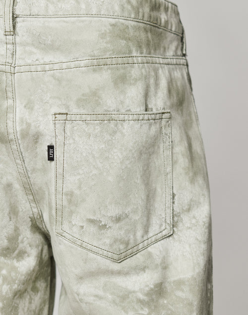Close-up of the back pocket on the LIVE FAST DIE YOUNG Rhomb Wide Denim jeans, featuring light-wash tie-dye, diamond panels, visible stitching, a black tag with white text, and a baggy fit made from 100% Baumwolle for comfort and style.