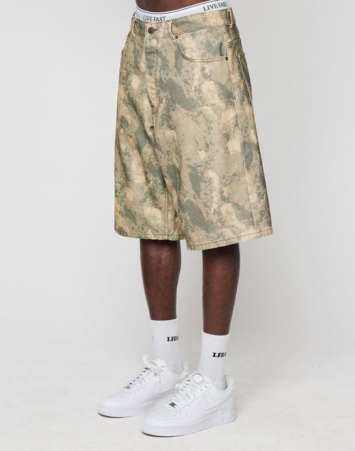 A person in LIVE FAST DIE YOUNG Canvas Shorts with a baggy fit and straight leg, white socks with LEDF text, and white Nike Air Force 1s stands against a plain white background.