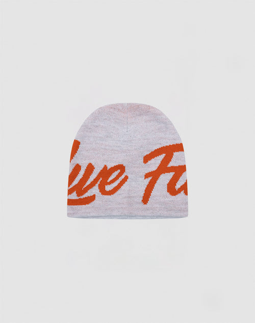 The LFDY Jacquard Beanie by LIVE FAST DIE YOUNG is a light gray knit beanie crafted from 100% Polyacryl, featuring bold orange cursive lettering across the front and shown against a plain white background.