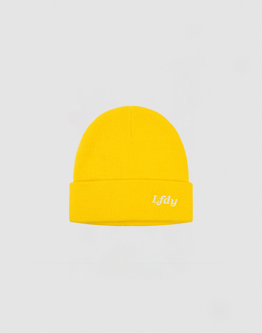 The LFDY Beanie by LIVE FAST DIE YOUNG is bright yellow, made from polyacryl, with a folded brim and white embroidered Lfdy Logo-Stick on the front, shown against a light gray background.