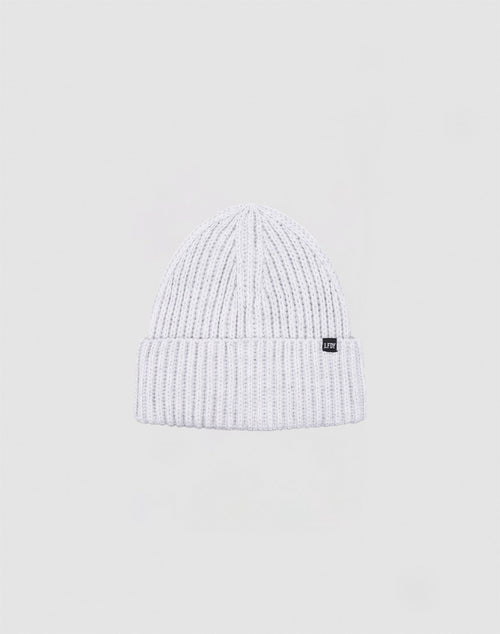 The LIVE FAST DIE YOUNG Rib Knit Beanie in white, crafted from soft polyacryl with a folded brim and a small black tag on the left, is shown against a plain light gray background.