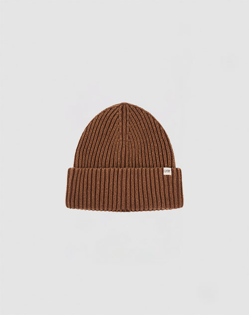 The LIVE FAST DIE YOUNG Washed Rib Knit Beanie in brown cotton features a folded cuff and a small white rectangular side tag, shown against a plain light gray background.
