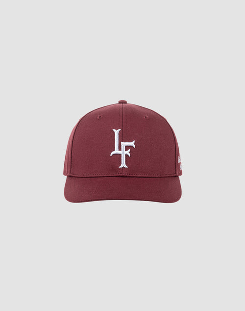 The LF Snapback by LIVE FAST DIE YOUNG is a maroon cotton baseball cap featuring a white LF logo embroidered on the front, shown against a light gray background. It includes a snap closure for an adjustable fit.