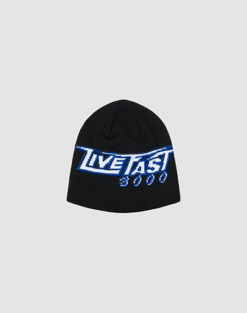 The LIVE FAST DIE YOUNG Live Fast 3000 Beanie is a black polyacryl hat featuring a blue and white LIVE FAST 3000 logo-strick graphic on the front, shown against a plain light gray background.