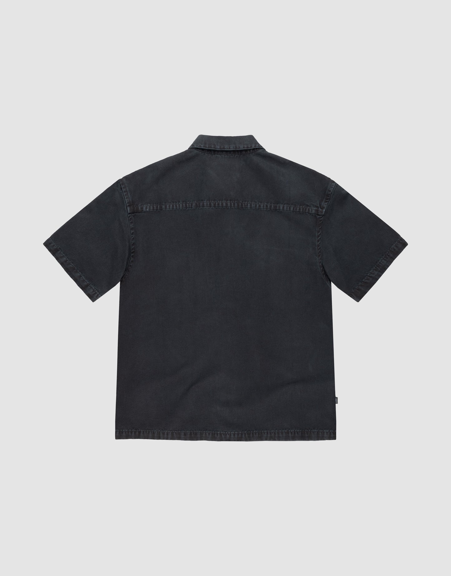 The LFDY Workwear Shirt by LIVE FAST DIE YOUNG is shown flat, back facing up, revealing its oversize fit, straight yoke, and simple collar. The dark short-sleeve button-up stands out against a plain light background.