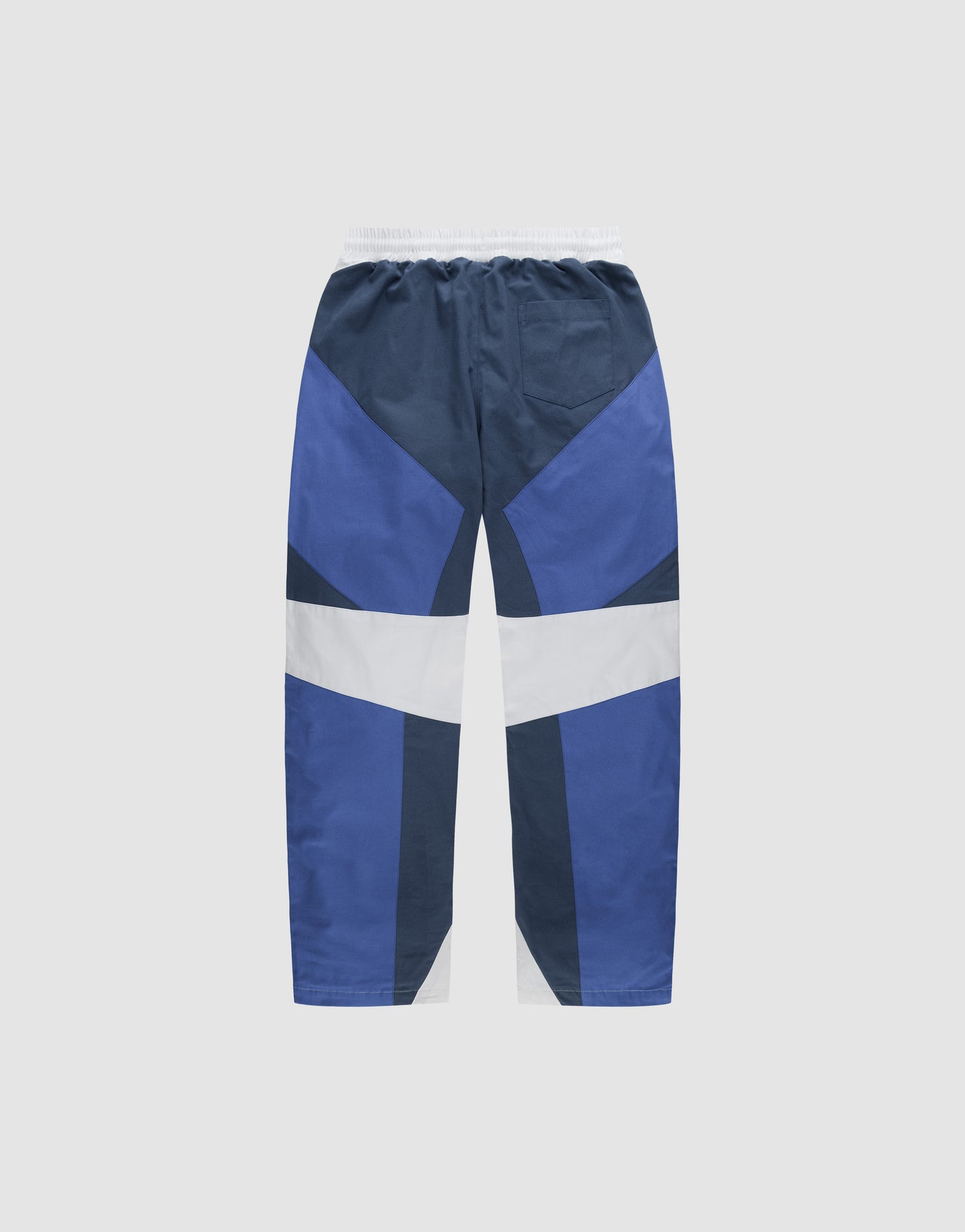 The LFDY Cross Pants by LIVE FAST DIE YOUNG feature an abstract geometric color-block design in navy, royal blue, and white. Made from cotton with a relaxed fit, elastic waistband, and wide legs, shown laid flat on a light gray background.