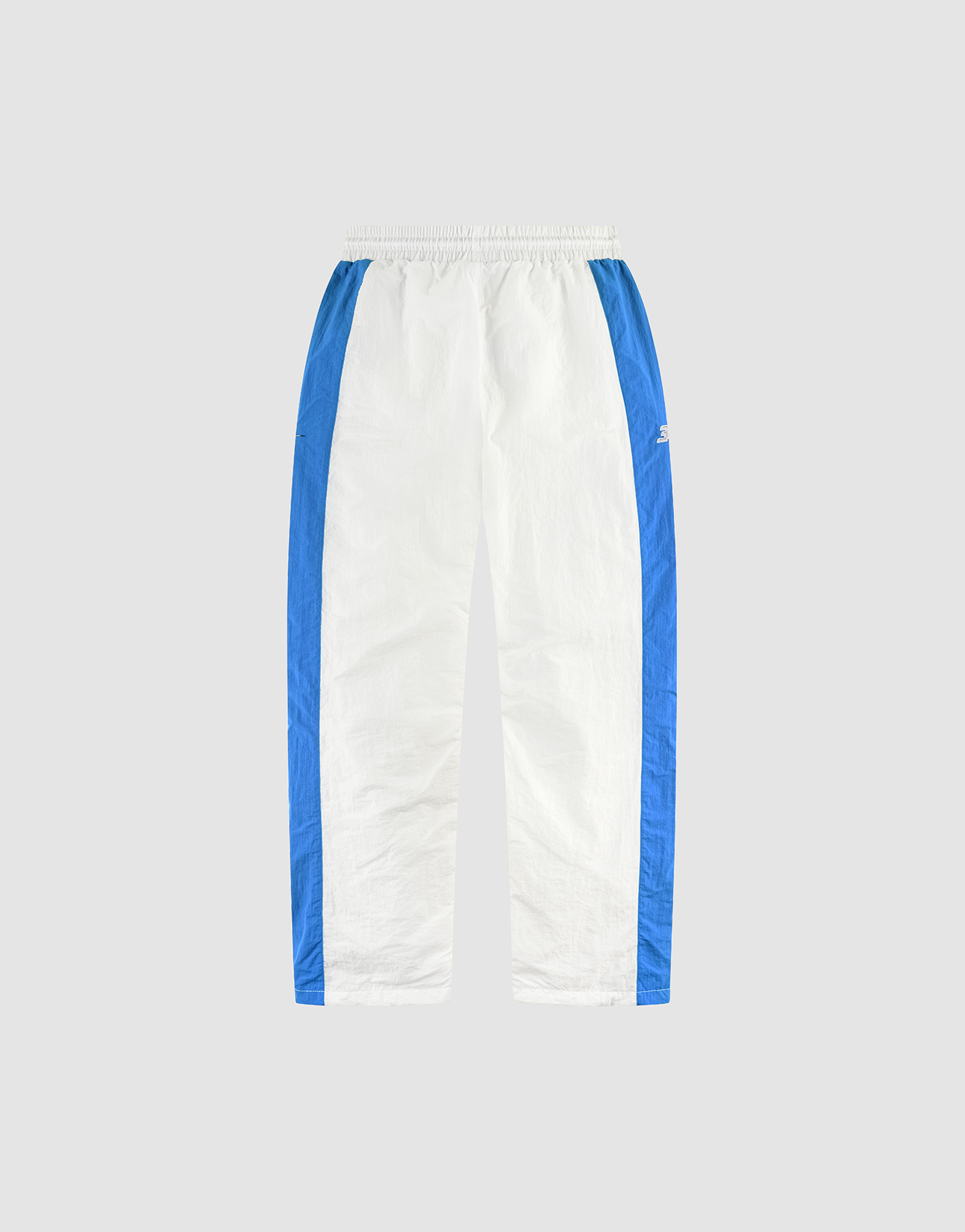 The LFDY Trackpants 3000 by LIVE FAST DIE YOUNG feature white fabric with blue side panels, an elastic waistband, side pockets, and a small logo on the upper left leg, shown against a plain light gray background.
