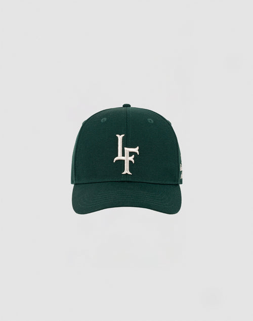 The LF Snapback by LIVE FAST DIE YOUNG is a dark green cap with a bold white LF logo embroidered on the front and a Mit Snapverschluss, shown against a plain light gray background. Model: LF2308-14417.