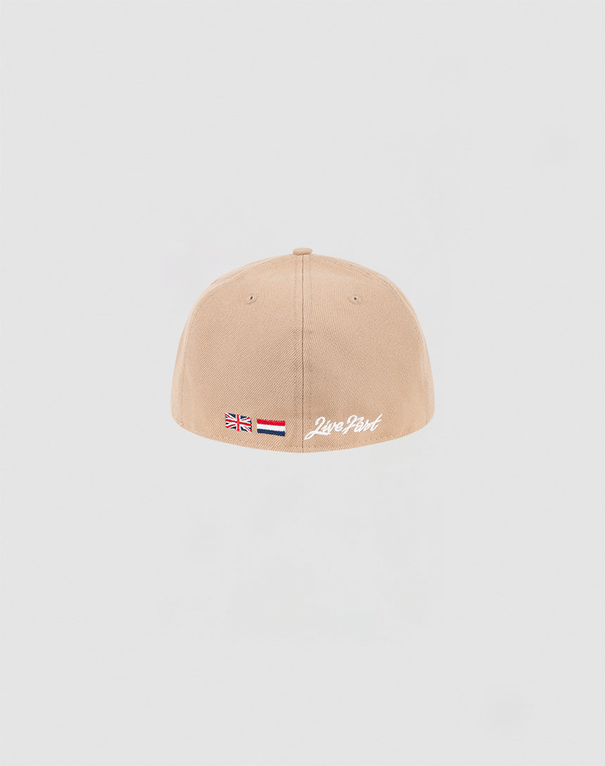 The LFDY x NEW ERA 59FIFTY Low Profile cap by LIVE FAST DIE YOUNG is beige, low profile, and fitted. The back shows small British and Dutch flags plus Live Fast in white embroidery near the bottom edge, styled in classic 59FIFTY fashion.