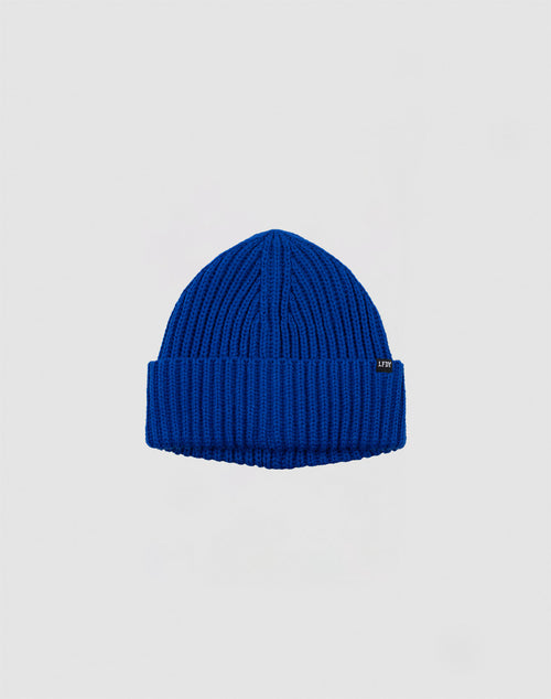 The LIVE FAST DIE YOUNG Rib Knit Beanie is a cozy blue Polyacryl hat with a folded brim, shown on a light grey background. One size for comfort and style.