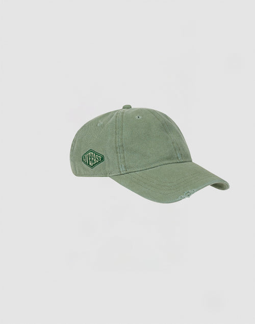 The Distressed Basic Cap by LIVE FAST DIE YOUNG is a faded green 100% Baumwolle baseball cap with a curved brim, distressed look, and an embroidered green and white patch reading NWT EAST on the side. Background: plain light gray.