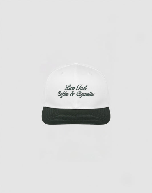 The LIVE FAST DIE YOUNG Live Fast Coffee Cap is a white, one size cap made from 100% Baumwolle with Live Fast Coffee & Cigarettes embroidered in dark green on the front, inspired by the LFDY Berlin Café and shown on a plain light gray background.