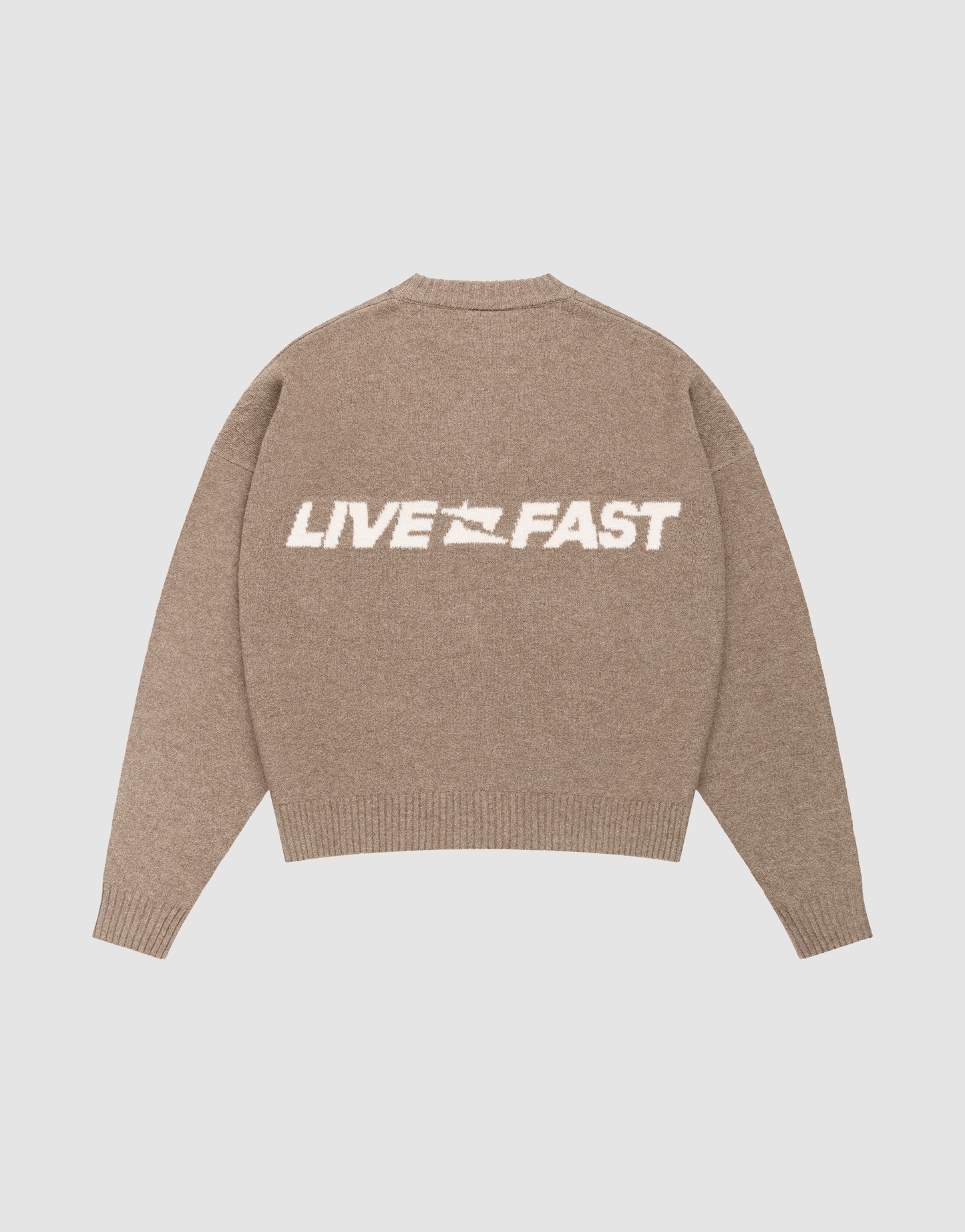 The LIVE FAST DIE YOUNG Live Fast Boucle Sweater is a beige, oversized knit featuring "LIVE FAST" in large white letters and a bold lightning bolt on the back, displayed flat on a light background.