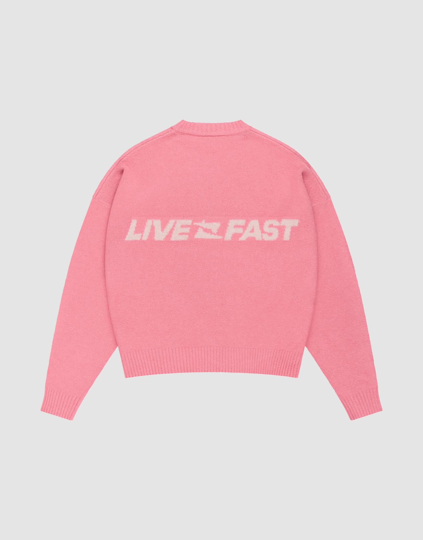 The Live Fast Boucle Sweater by LIVE FAST DIE YOUNG is a pink oversized sweater with soft polyester and ribbed trims, featuring white "LIVE FAST" text and a racing flag graphic on the back.