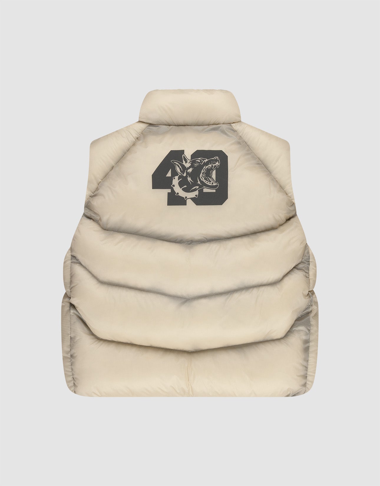 The LIVE FAST DIE YOUNG Live Fast Puffer Vest is a beige, oversize-fit vest with a back view showing a black '49' graphic and illustrated shark head on the upper back.