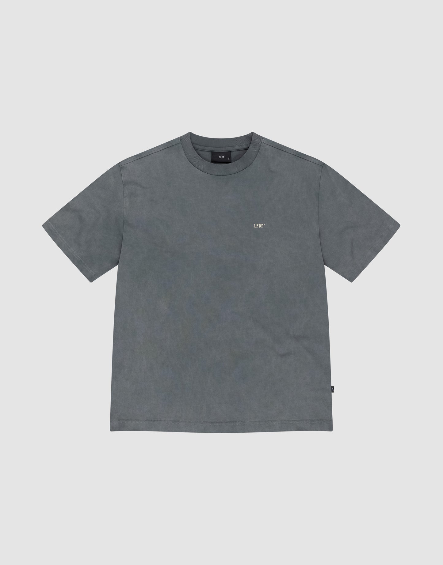 The Basic Trademark Tee by LIVE FAST DIE YOUNG is a plain, short-sleeved, faded gray shirt with a small white LIF logo on the left chest, made from 100% Baumwolle and shown flat on a light gray background.
