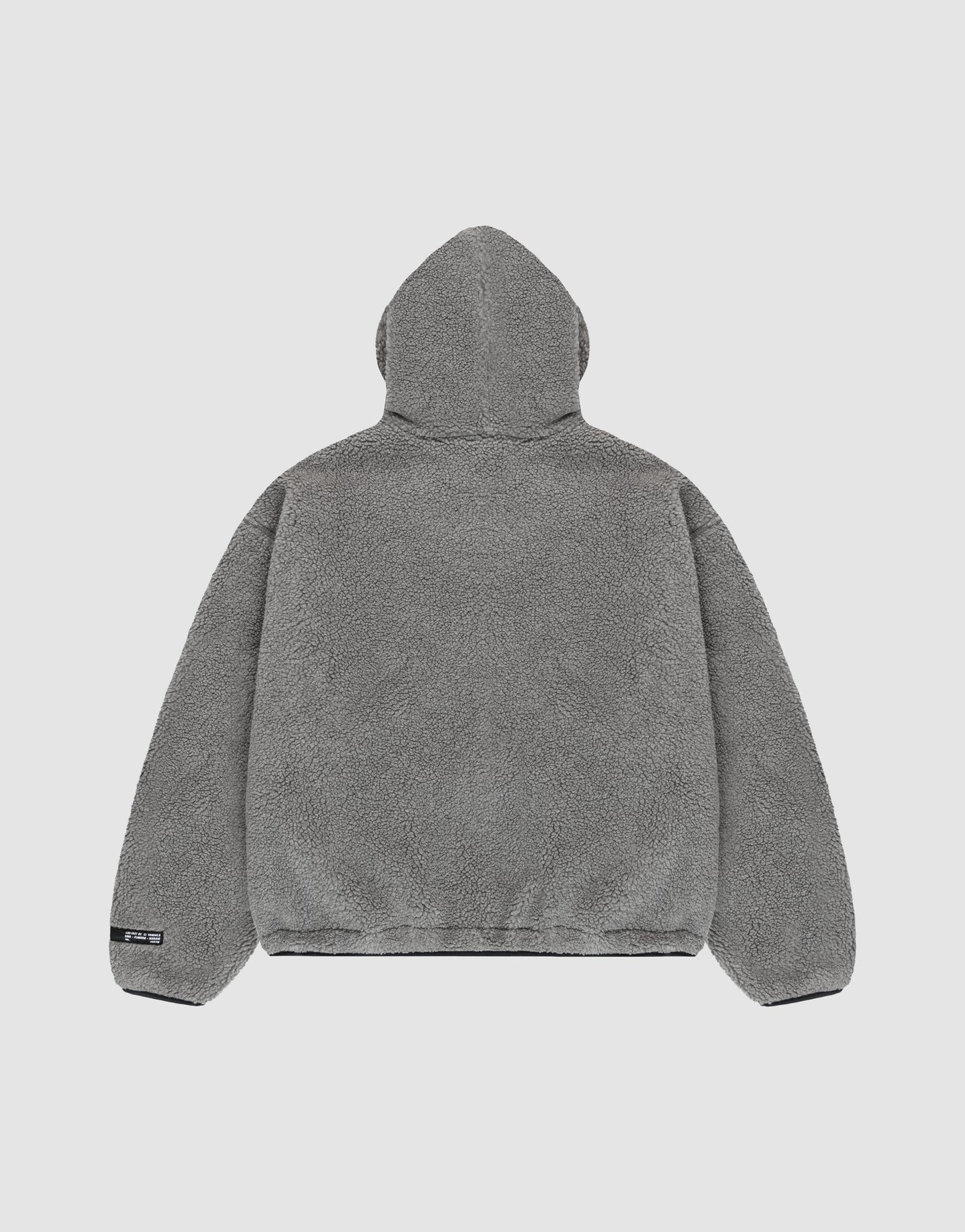 The LIVE FAST DIE YOUNG LFDY Teddy Hooded jacket in gray fleece is shown from the back on a plain light background. It features a soft, plush texture, oversize fit, long sleeves, and a small black tag on the lower left hem.