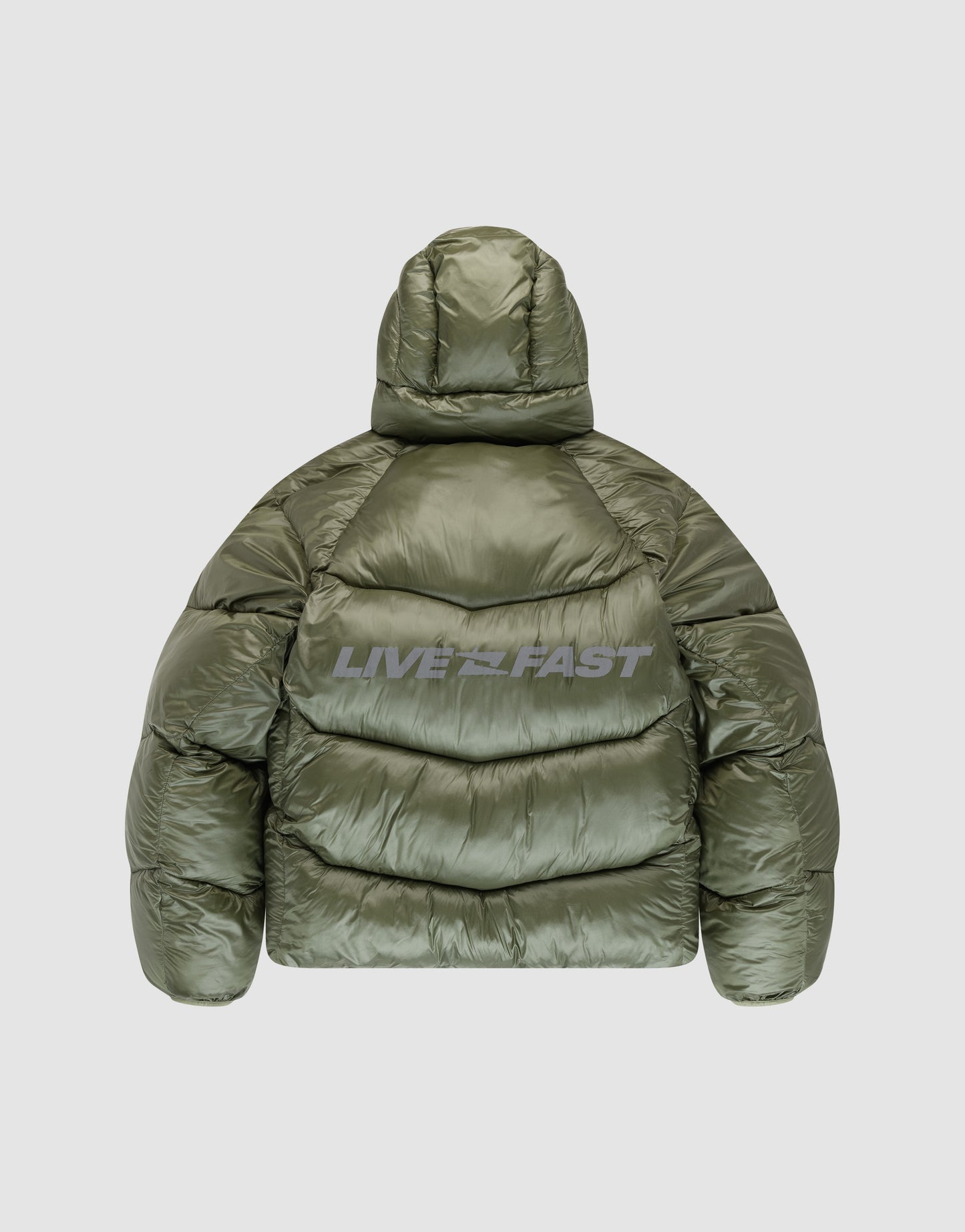 The LIVE FAST DIE YOUNG Live Fast Puffer Jacket in olive green nylon features an oversized fit with hood and “LIVE FAST” reflective back print. Shown from the back against a light gray background.