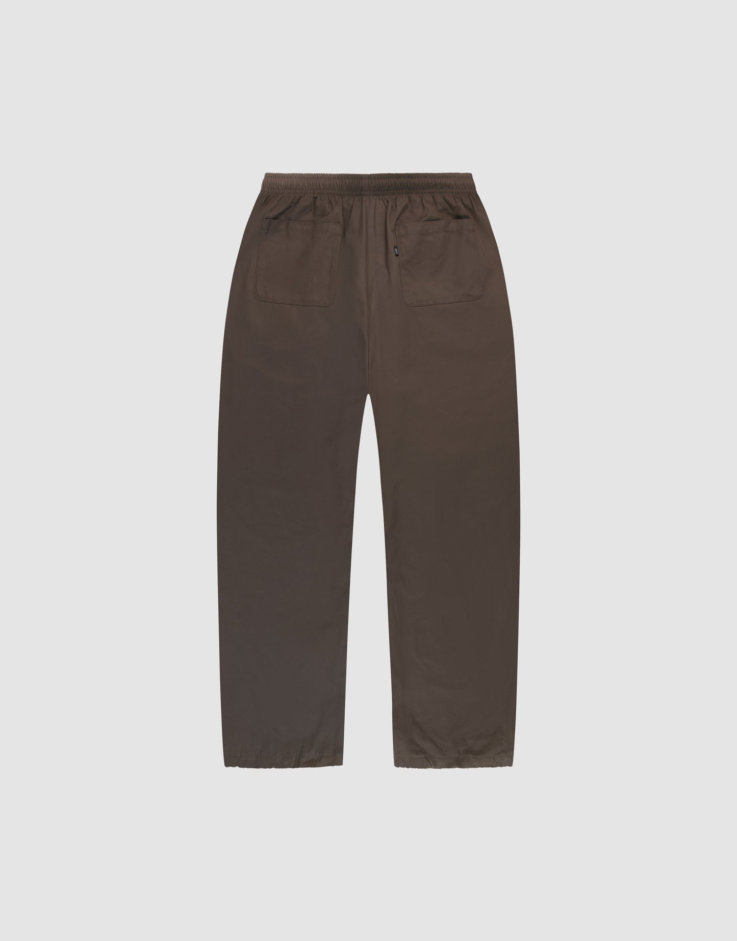 LIVE FAST DIE YOUNG Baggy Nylon Pants in brown wide fit, shown flat from the back on a light gray background, feature an elastikbund, two back pockets (one with button), and practical seitliche Eingrifftaschen.