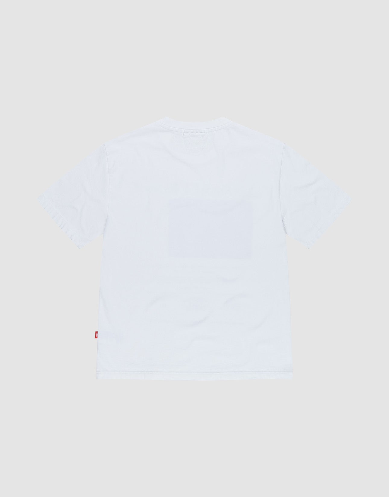 The LIVE FAST DIE YOUNG LFDY SiXXXth Store Tee is an oversized, plain white short-sleeve T-shirt made from 100% Baumwolle, shown from the back with a small red tag on the left seam near the hem and no other visible designs.