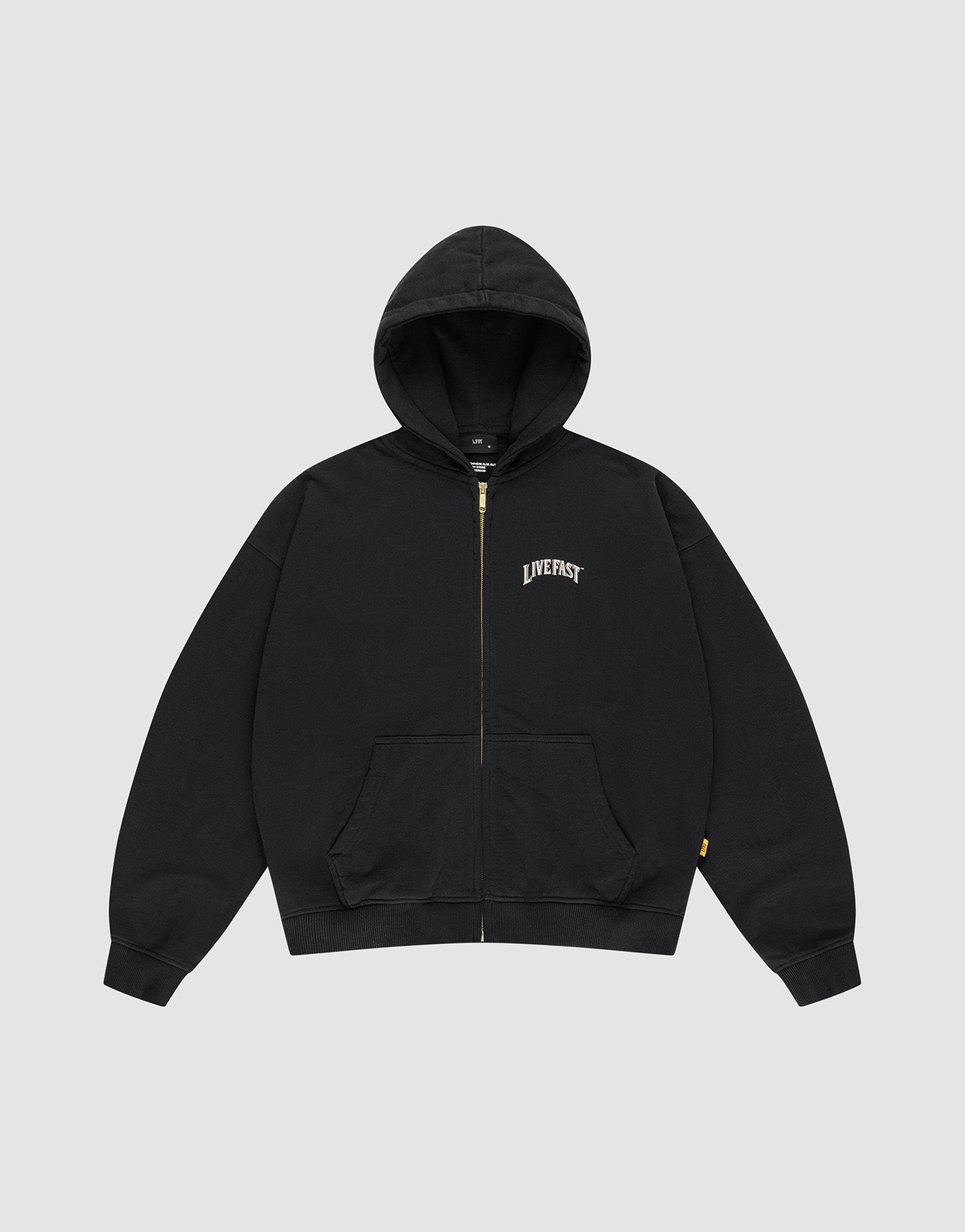 The LFDY x The Bulldog Hooded Zip by LIVE FAST DIE YOUNG is an oversized black zip-up hoodie with front pockets, a hood, and "LIVE FAST" in a white logo print on the left chest. It is shown flat on a plain light gray background.
