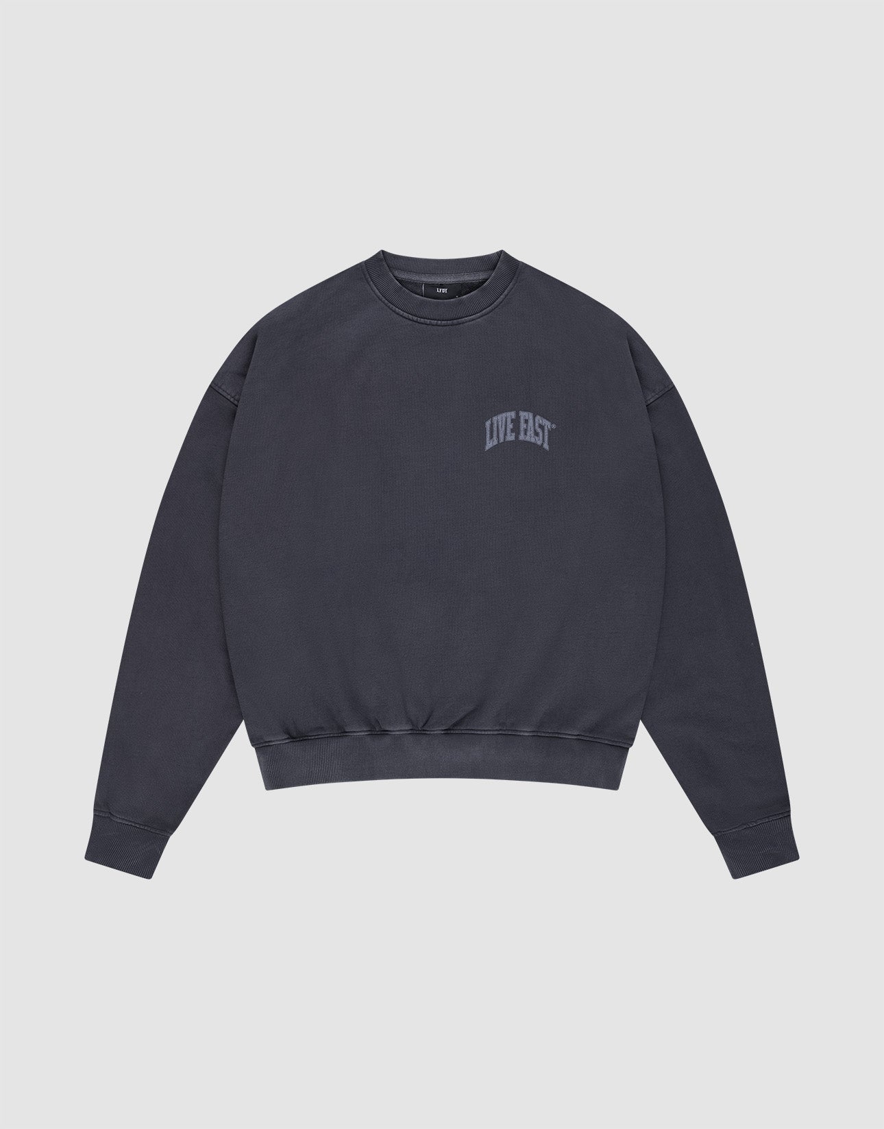 The Live Fast Berlin Sweater by LIVE FAST DIE YOUNG is a dark gray, oversized crewneck made from 100% cotton. It features "LIVE FAST" in small light gray letters on the left chest, set against a light background.