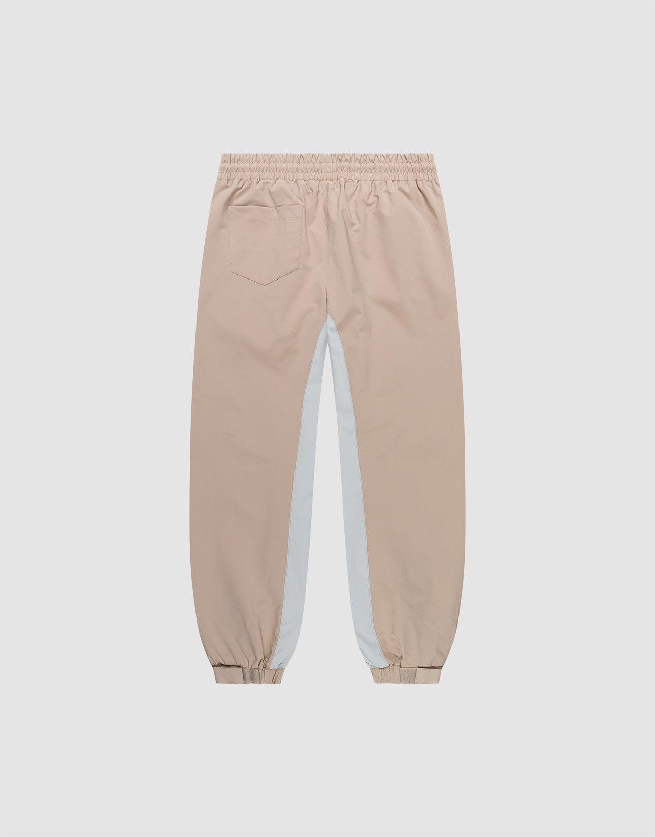 The LIVE FAST DIE YOUNG Basic Shell Pants feature an elastic waistband and cuffs, a single back pocket, oversize fit, and a white panel with reflective print down each leg. Shown on a plain light background.