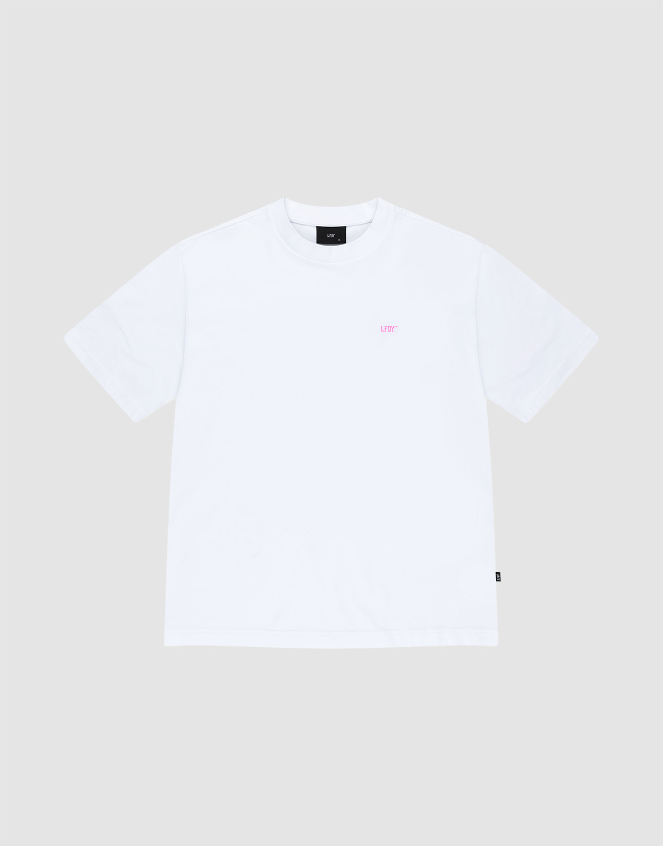 The LIVE FAST DIE YOUNG Basic Evidence Tee is a plain white oversized short-sleeve shirt made from 100% cotton, shown laid flat on a light gray background with small pink LEFT text on the upper left chest.