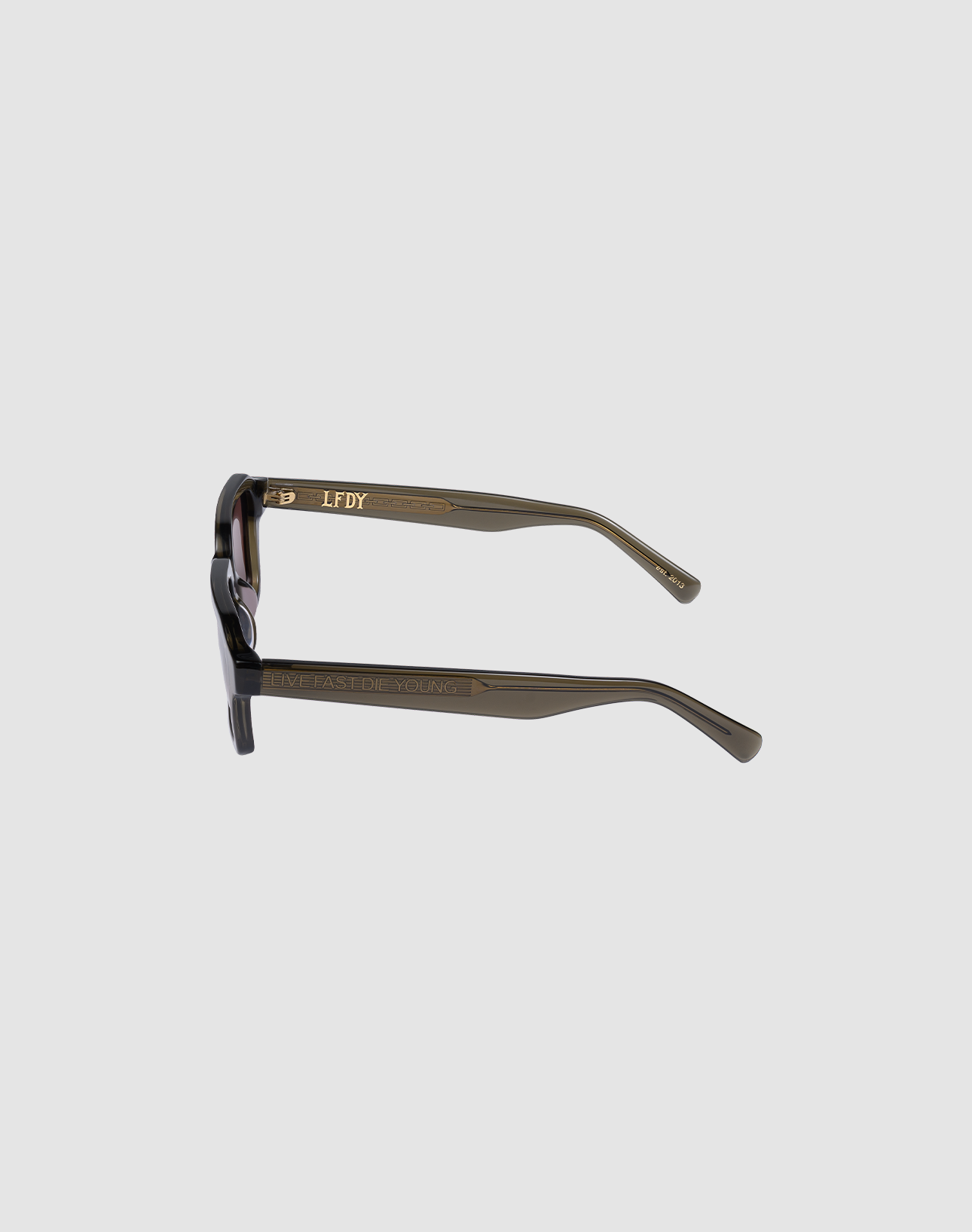 The LFDY Forma sunglasses by LIVE FAST DIE YOUNG feature dark green, gläsern, translucent arms with gold "LIVE FAST DIE YOUNG" and "LFDY" text on a light gray background. Comes with a matching Reinigungstuch.