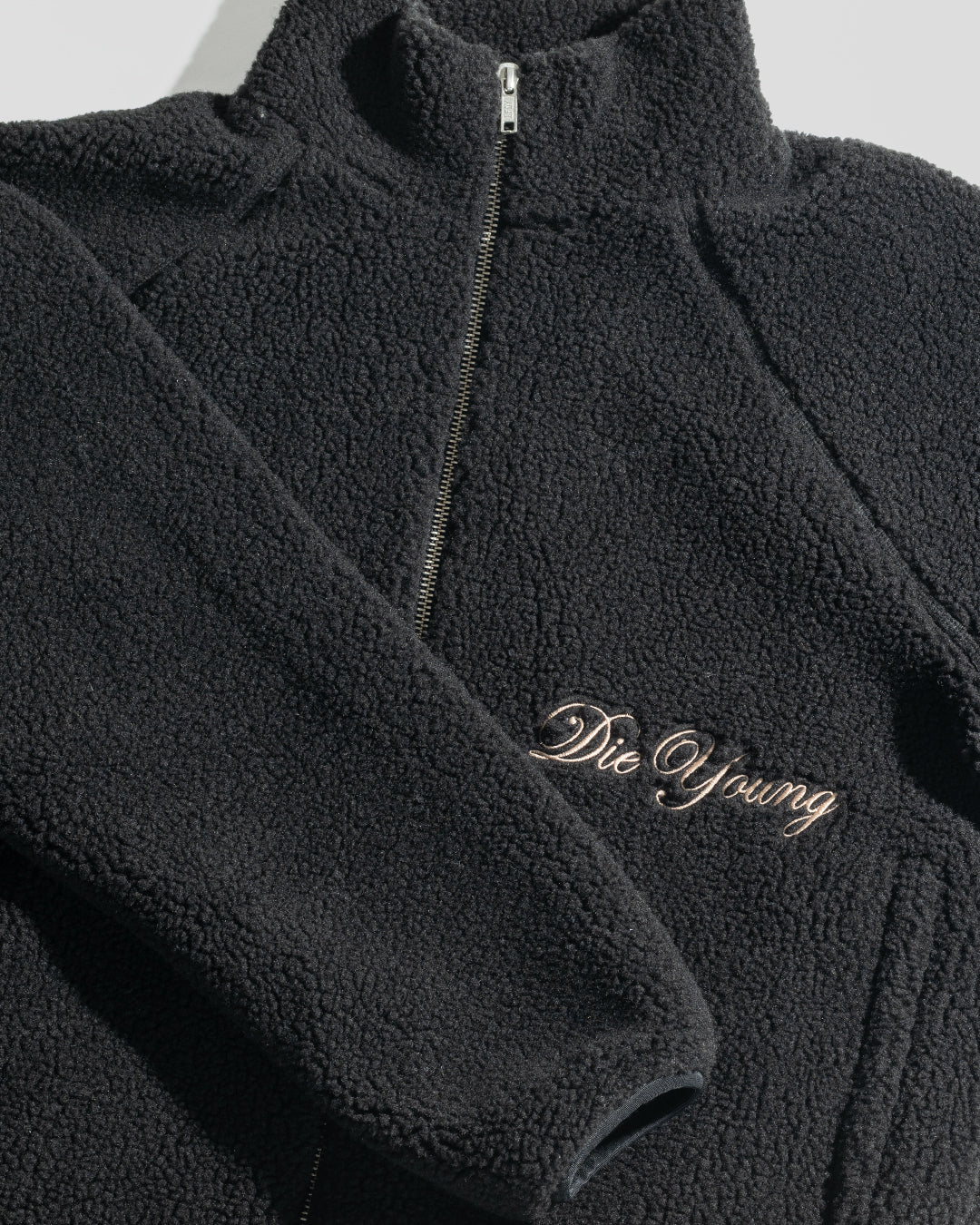 The LFDY Teddy Jacket by LIVE FAST DIE YOUNG is a black oversized jacket with textured fabric, raglan sleeves, a zipper, and “Die Young” embroidered in cursive on the front.
