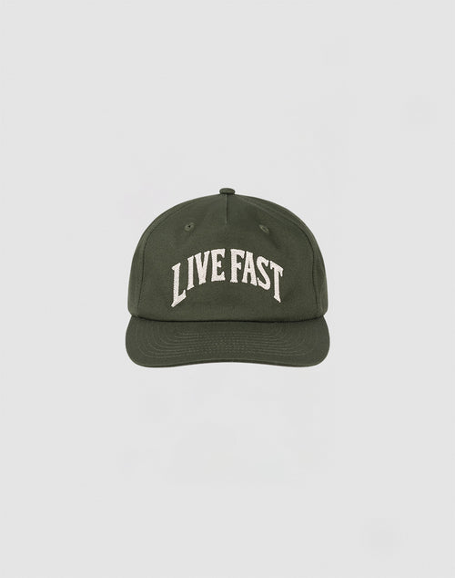 The Live Fast Unstructured Cap by LIVE FAST DIE YOUNG is a dark green 100% Baumwolle baseball cap with LIVE FAST boldly embroidered on the front and a subtle Flag Label, shown against a plain light background.