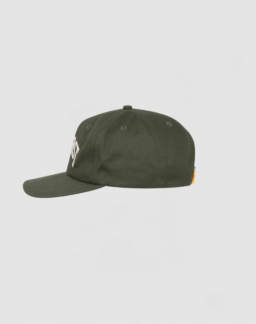 The Live Fast Unstructured Cap by LIVE FAST DIE YOUNG is a dark green 100% cotton baseball cap with a flat brim, bold white logo embroidery on the front, and an orange flag label on the back, shown from the side against a light gray background.