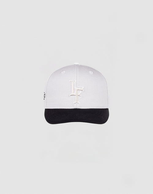 The LF Snapback by LIVE FAST DIE YOUNG features a white cap with a white LF logo, black brim with black underside, and snap closure, shown on a plain light gray background.