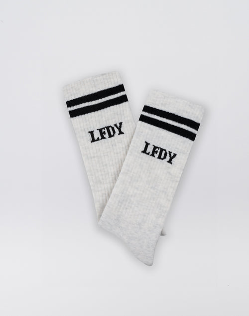 The LIVE FAST DIE YOUNG Basic Socks (2 Pack) are white, crafted from a soft Baumwolle blend, with two black stripes near the top and LFDY printed below, shown against a plain white background.