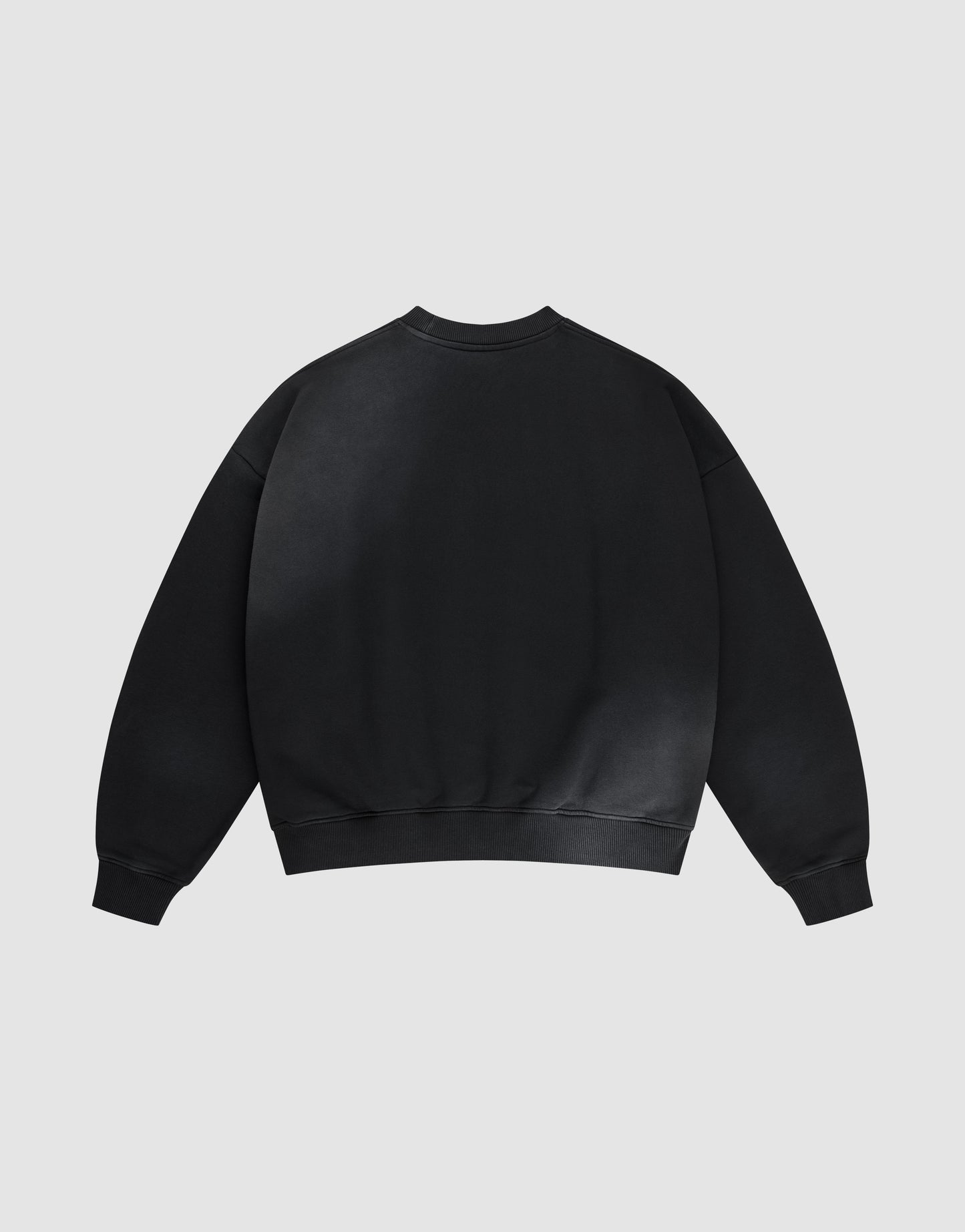 The LIVE FAST DIE YOUNG Live Fast Rhinestone Sweater, an oversized black crewneck with long sleeves and ribbed cuffs, collar, and hem, is laid flat and shown from the back against a light gray background.