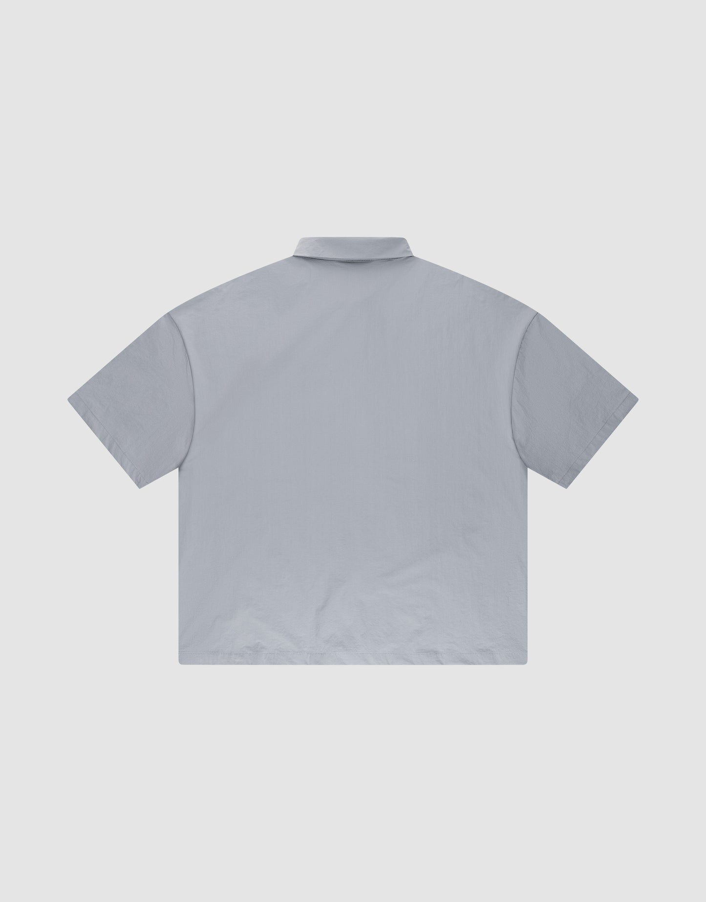 The LFDY Ripstop Shirt by LIVE FAST DIE YOUNG is shown flat with the back facing up against a white background. It features a hemmed collar, oversize fit, and a minimalist light gray design.