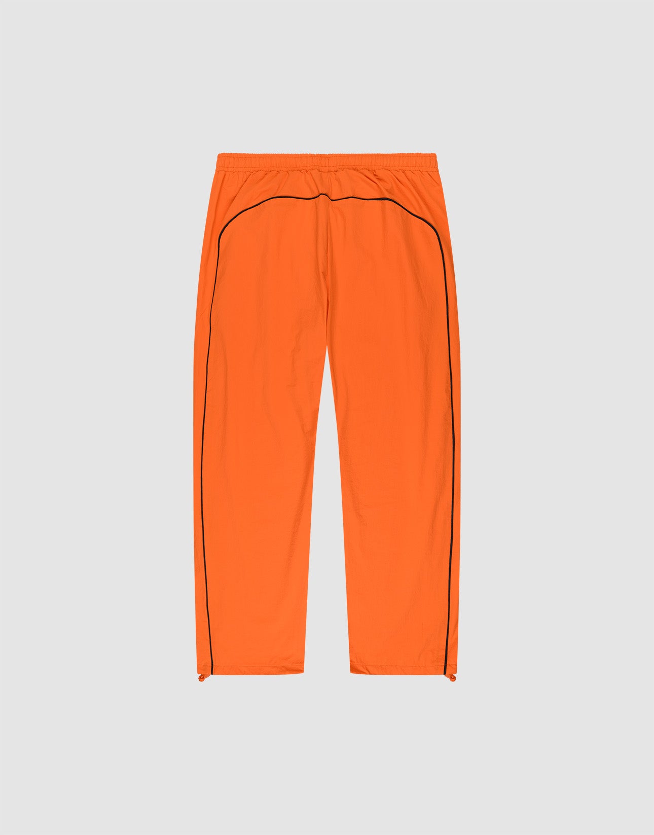 The LIVE FAST DIE YOUNG Live Fast Trackpants are bright orange, wide fit with an elastic waistband, black side piping, and a reflective logo print, shown flat on a light gray background.