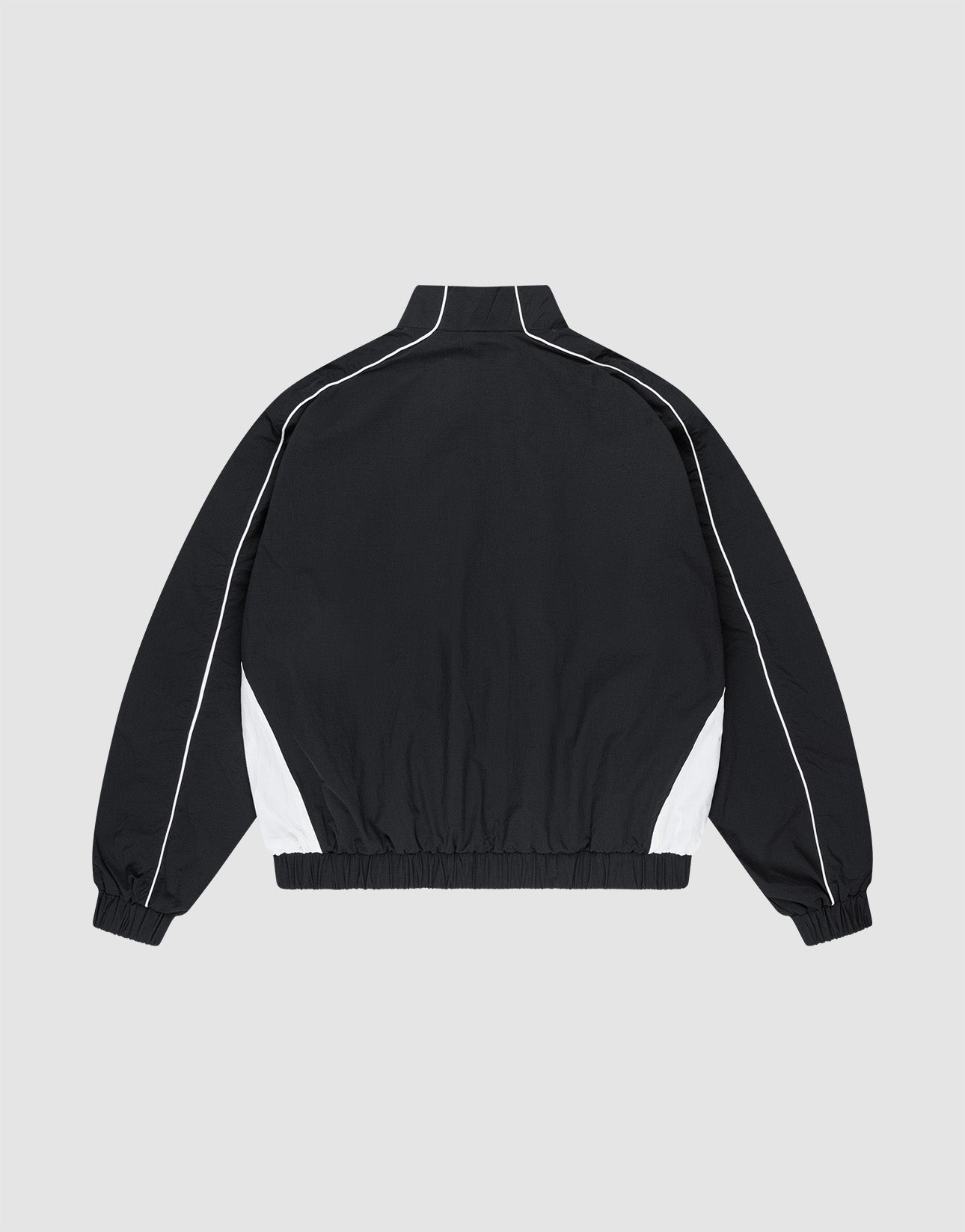 The Basic Nylon Trackjacket by LIVE FAST DIE YOUNG is shown from the back in black with white side panels, high collar, piping, logo on the back, elastic cuffs and waistband, and side slit pockets against a light gray background.