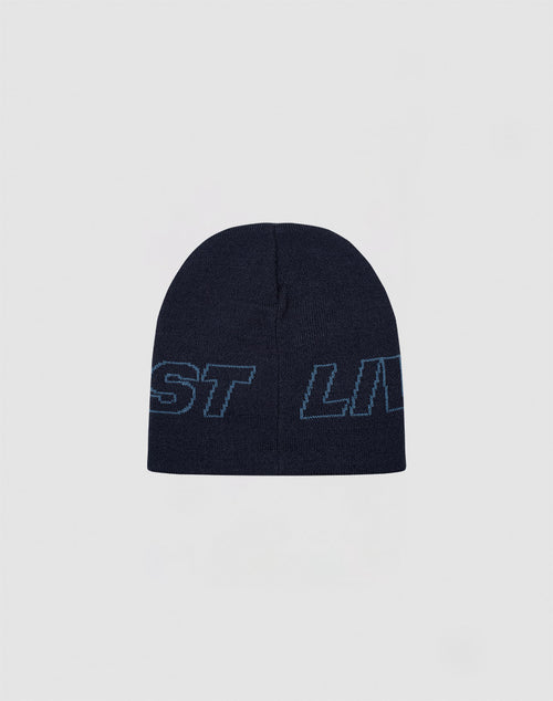 The Live Fast Jacquard Beanie by LIVE FAST DIE YOUNG is a dark navy polyacryl knit hat with light blue outlined “Logo Strick Outline” text wrapping around it, shown against a plain light gray background.