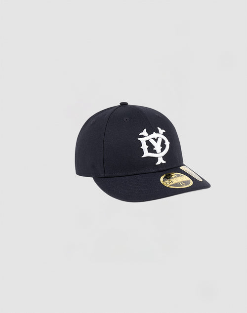 A dark navy LFDY x NEW ERA 59FIFTY Low Profile fitted cap by LIVE FAST DIE YOUNG features a white embroidered front logo and gold brim sticker, displayed on a plain light gray background.