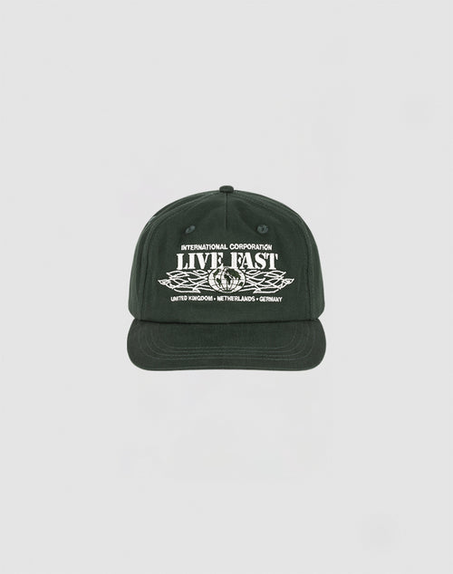 The Live Fast Corporation Cap by LIVE FAST DIE YOUNG is a black 5-panel cap with white INTERNATIONAL CORPORATION LIVE FAST text above wings and country names below, featuring a Multi-Logo design on a plain light background.