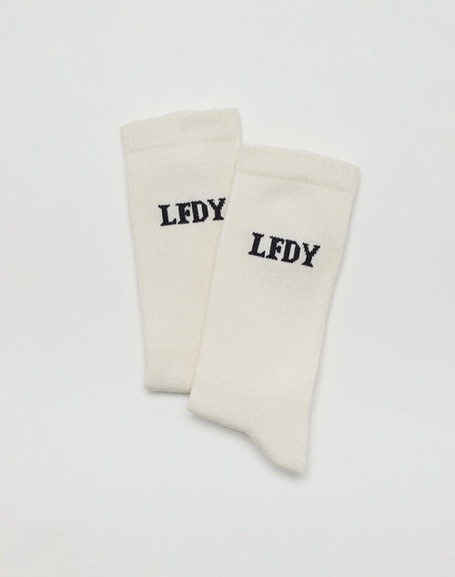 The LFDY Logo Socks (2 Pack) by LIVE FAST DIE YOUNG are white, made from soft cotton, and feature black LFDY lettering on the sides, shown against a plain white background.